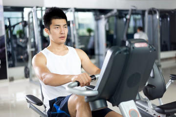 Fototapeta na wymiar young handsome man working out in modern gym