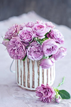 Beautiful purple rose flowers in a vase .