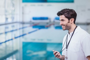 Handsome trainer holding stopwatch at the pool
