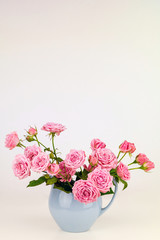 Pink flowers in blue jug. Roses in jug.