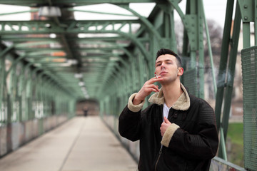 Attractive young man smoking a cigarette on the street