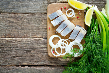 herring onion and herbs on wooden surface