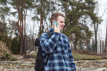 Fototapeta premium guy in town with a backpack talking on the phone