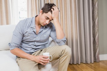 Stressed young man sitting on sofa