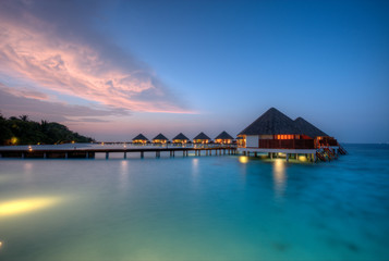Water villas on Maldives resort island in sunset