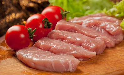 Raw pork оn the wood board. Tomato and lettice