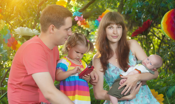 happy young family relaxing in the park.little girl enthusiastically playing a computer game on the phone. addiction