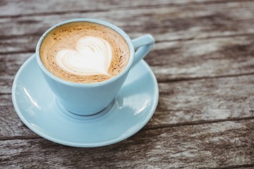 Cup of cappuccino with coffee art on wooden table