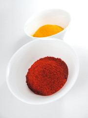 Dried paprika or red bell pepper spice and curry in white bowls