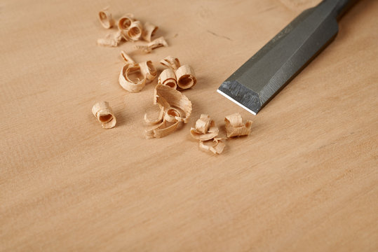 Woodworking tool. A chisel with shavings on workbench.