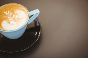 Cup of cappuccino with coffee art on wooden table