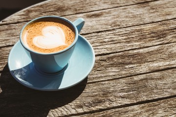 Cup of cappuccino with coffee art on wooden table