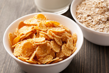 Cornflakes and oatmeal in white bowls with milk