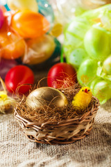 Golden easter egg and chicken in small basket with colorful  bac