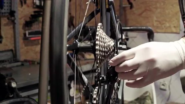 Mechanic repairing bicycle in workshop. Close up. Slider shoot