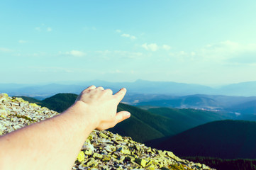 Young man standing on rock and pointing by his finger