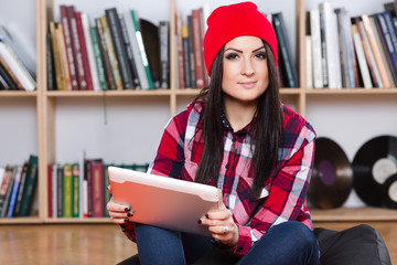 Beautiful brunette wearing red plaid shirt sitting with tablet