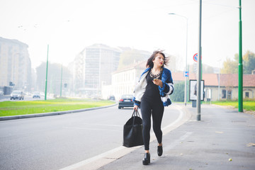 Young handsome eastern woman walking outdoor in the city, holdin