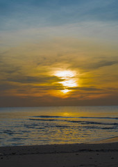 Fototapeta premium Sun sets over horizon of ocean. Sky, water and shore in the even