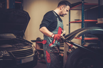Professional car  mechanic balancing car wheel on balancer in au
