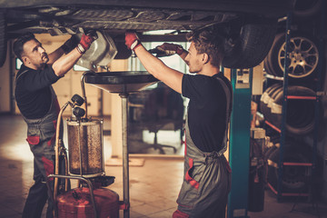 Professional car  mechanic changing motor oil in automobile engi