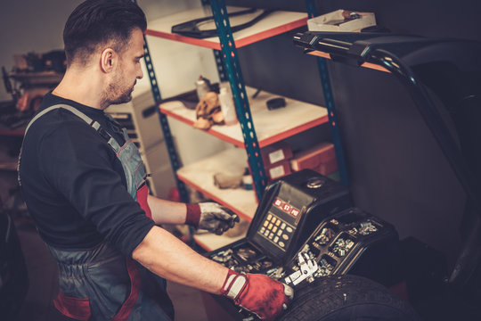 Professional car  mechanic balancing car wheel on balancer in au