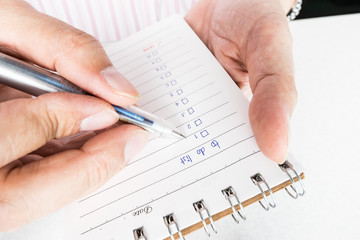 Close-up of hand holding person's hand writing things To Do List on paper / notepad