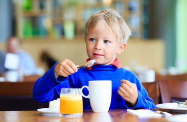 little boy eating breakfast in cafe