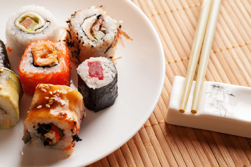 Sushi rolls on a white plate with chopsticks, closeup