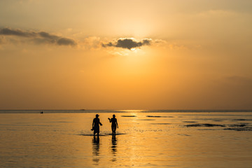 Silhouette couple walking in the sea