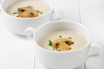 Mushroom cream soup in white bowls on wooden boards