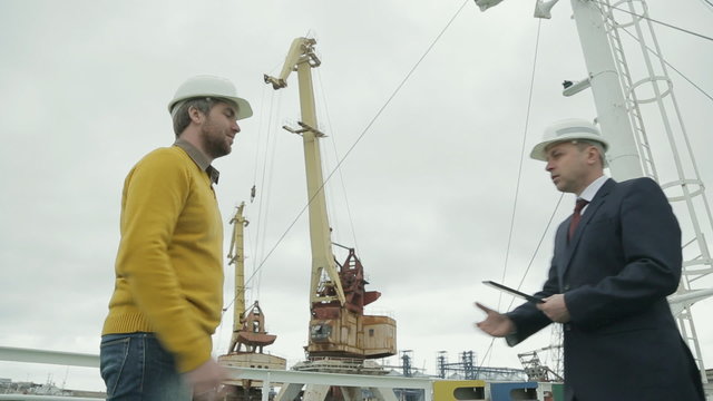Discussion of a major business project by two businessmen on port
