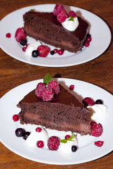 Two portions of chocolate dessert decorated with forest fruits and ice cream on the wooden rustic table