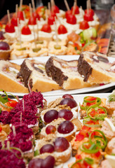 Full tray of fresh food as a vegetarian beetroot and smoked salmon canapes as well as chocolate homemade dessert with fruit and cream, colorful table