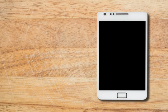 White smart phone with isolated screen on old wooden desk