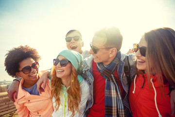 smiling friends in sunglasses laughing on street