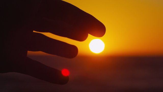 Pacific Sun Ball (4K) - A slow motion silhouette hand waving against setting sun on Pacific Ocean.