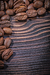 Heap of coffee beans on vintage wooden board top view