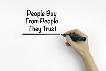 Hand with marker writing: People Buy From People They Trust