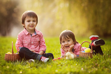 Two boys in the park, having fun with colored eggs for Easter