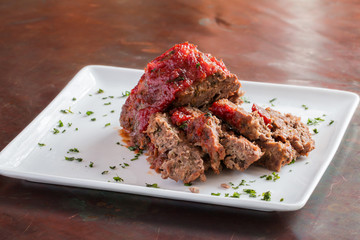 Sliced freshly cooked traditional meatloaf with ketchup tomato sauce isolated on white plate - 104084623