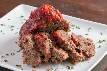 Sliced freshly cooked traditional meatloaf with ketchup tomato sauce isolated on white plate - 104084689