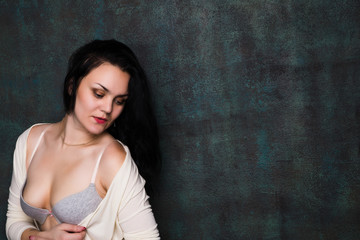Obraz premium Studio portrait of a sexy brunette in grey lingerie and white cardigan