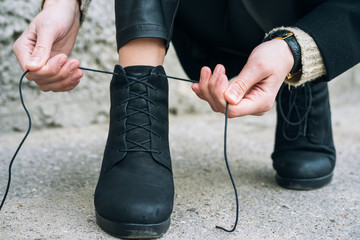 Woman in elegant clothes tying shoelaces on shoes close up