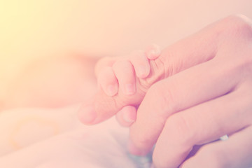 Newborn baby hand touch on mother hand in warm tone, vintage pic