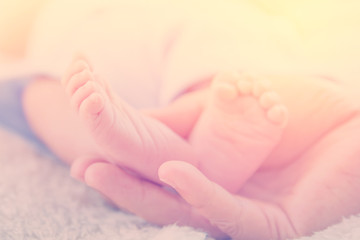 Newborn baby feet on mother hand in warm tone, vintage picture s