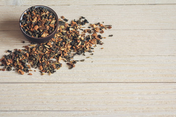 Dry exotic tea with spices in dark ceramic bowls