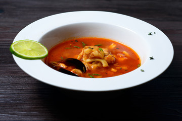 Delicious soup with mussels on black background