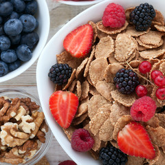 Berries, strawberries, raspberries, currants, blackberries, blueberries, nuts, milk and muesli  ingredients for healthy breakfast  on white wooden table.