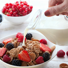 Berries, strawberries, raspberries, currants, blackberries, blueberries, nuts, milk and muesli  ingredients for healthy breakfast  on white wooden table.